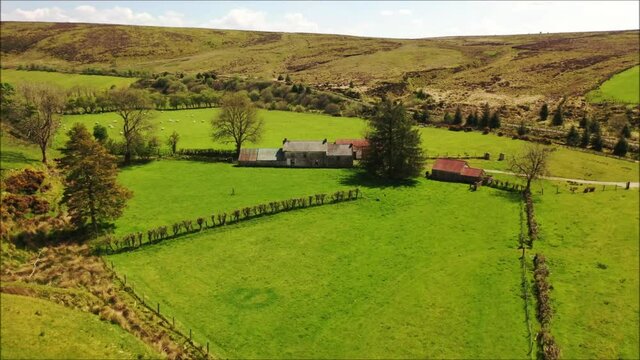 Drone footage of Irish countryside within the Sperrins showing lush fields and derelict houses.