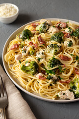 Homemade Chicken Bacon Broccoli Alfredo on a plate on a gray surface, side view.
