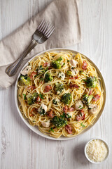 Homemade Chicken Bacon Broccoli Alfredo on a plate on a white wooden background, top view. Flat lay, overhead, from above.