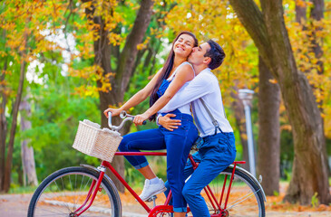Fototapeta na wymiar Teen couple with retro bike kissing in the park in autumn time