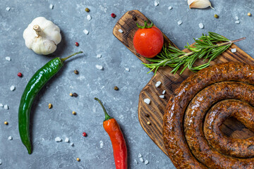 Spiral grilled sausages on wooden serving board.
