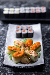 set of sushi rolls with seafood on a black stone background
