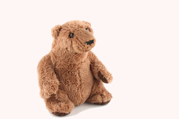soft toy brown bear sitting down, isolated on white background with copy space