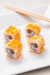 California sushi rolls on white plate with chopsticks