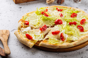Top view on caesar pizza with iceberg salad and tomatoes
