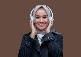 Hijab woman posing wearing wireless headphones with a smile.