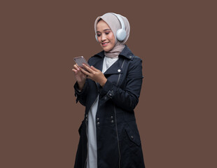 Hijab woman wearing headphones was touching her cell phone screen.