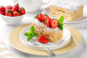 A slice of Napoleon cake with strawberries and mint. Russian cuisine, layer cake with cream, close up.