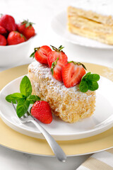 A slice of Napoleon cake with strawberries and mint. Russian cuisine, layer cake with cream, close up. Vertical orientation.
