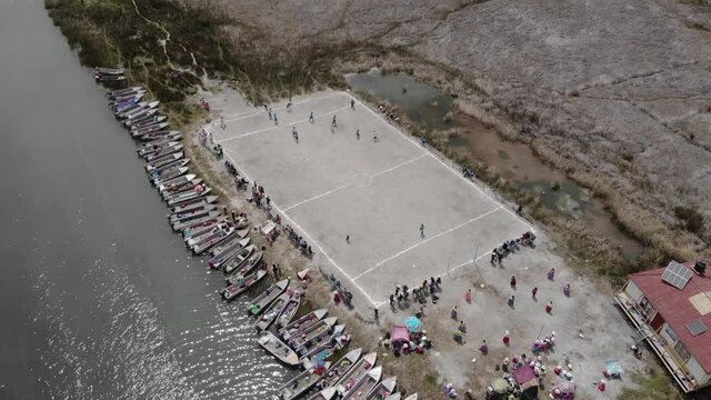 Aerial tilt shift: Boats lined up as kids play soccer on Lake Titicaca