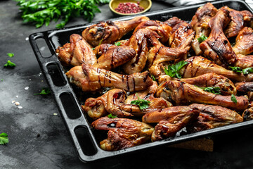 Fried golden chicken wings and legs on baking tray. Oven baked chicken pieces. Restaurant menu, dieting, cookbook recipe