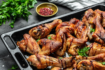 Baked chicken wings and legs on baking tray. Wings of barbecue on dark stone table. Top view, Food recipe background. Close up