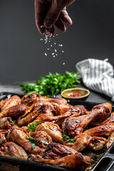 Hot Chicken wings and legs with celery, Cook hand sprinkling salad with meat in a freeze motion. Food recipe background. Close up
