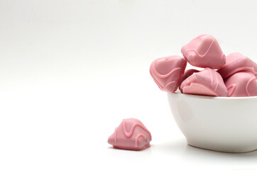 White bowl full of pink candies on the white background