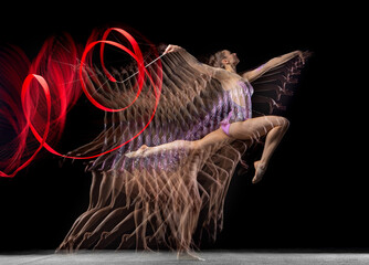 Young graceful girl rhythmic gymnast in motion isolated in mixed light on dark background.