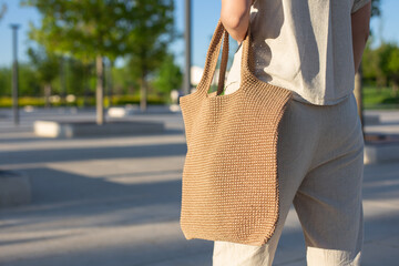 Woman holding brown knitted handmade bag in the hand outdoors. Sustainable shopping. Zero waste...