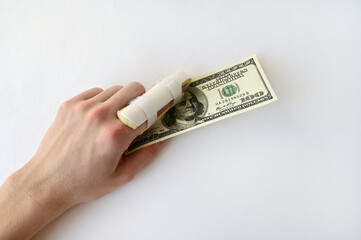 medical splint on a broken finger and money on a white background. Paid medical care for injuries. Copy space