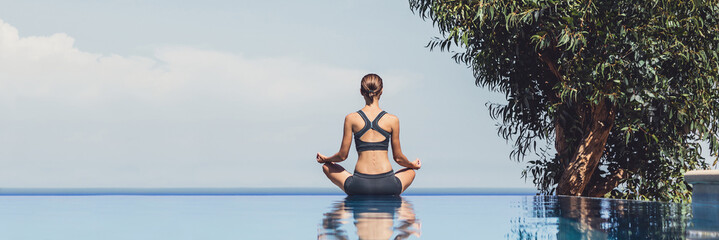 Young woman practicing yoga outdoors. Recreation, self care, yoga training, fitness, breathing exercises, meditation, relaxation, healthy lifestyle concept. Panoramic banner