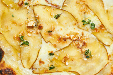 Delicious Italian wood fired pizza with creamy sauce, cashews, pear, mozzarella and gorgonzola on a gray background. Hard light.