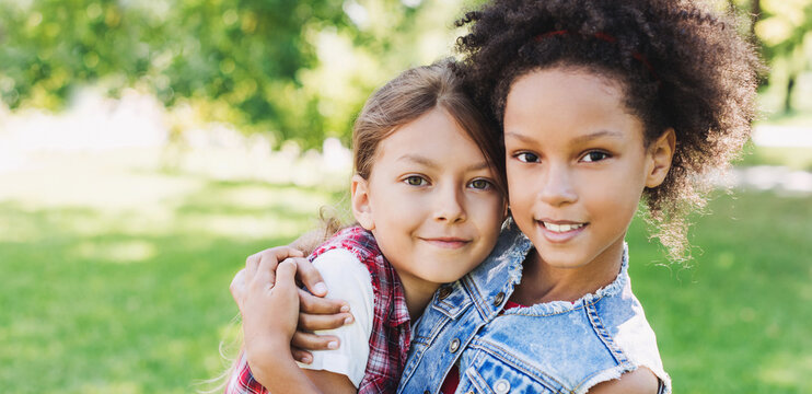 Two Little Girls Hugging In The Park. Diverse Multi Ethnic Kids Friends Playing Together Outdoor. Summer Fun, Friendship, Diversity, Vacations Concept	