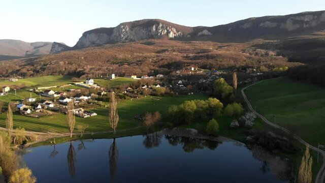 Village at green mountain valley aerial. Scottish hillside town with sea lake, castle ruins. Rural nobody nature landscape.