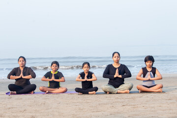 Group of people meditating in a row at the beach - obrazy, fototapety, plakaty