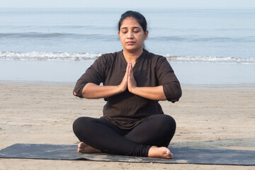 Fototapeta premium Woman meditating in prayer pose at seafront