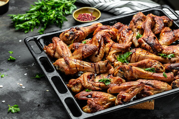 Chicken wings and legs with sauce. Wings of barbecue on dark stone table. Top view, Food recipe background. Close up