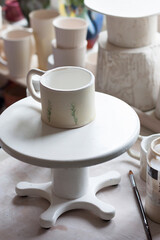 A ceramic mug stands on the turnstile. Ceramist's Workshop