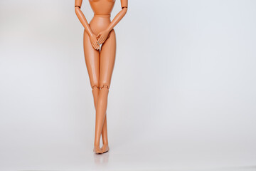 Nude doll covering pelvic area white background