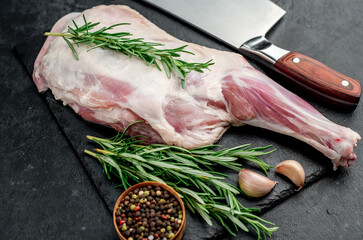 raw lamb shoulder blade with rosemary on stone background
