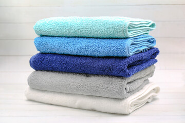 Stack of colorful towels on white wooden table.