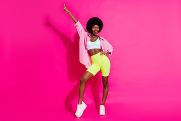 Fototapeta na wymiar Photo of funny sweet dark skin woman dressed crop top smiling dancing pointing finger isolated pink color background