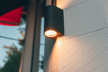 A photo of a lamppost on a modern building lighting the exterior walls of the construction in the...