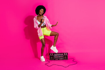 Fototapeta na wymiar Photo of funky charming dark skin woman dressed crop top smiling singing mic boombox empty space isolated pink color background