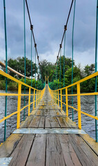 Perspective view of suspension bridge over river on cloudy day