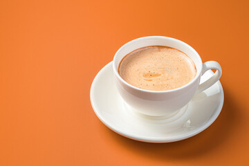 White coffee cup on orange background with copy space. Side view.