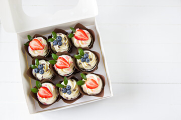 Cupcakes  decorated with strawberry and blueberries  in delivery paper box. Sweet food delivery