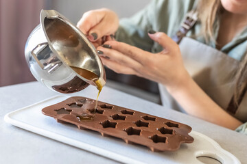 Soap maker a woman pours hot organic cocoa butter with aromatic oils into molds for making...