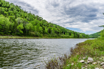 Fototapeta na wymiar View on the Matapedia river in the province of Quebec (Canada) on a cloudy summer day