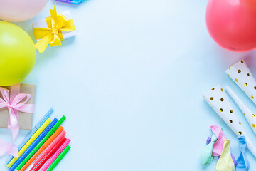 Colorful party invitation background with presents, color markers and balloons on light blue background. Image with copy space in the middle