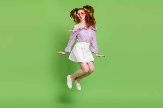Full length photo of flirty orange hairstyle millennial lady jump wear blouse spectacles skirt isolated on green color background