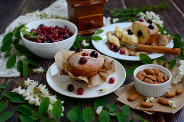 Cupcakes with fresh black and red currants on a wooden table. Tasty breakfast