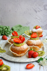 Vertical view of fresh strawberry and kiwi cakes on a metal tray. Close-up. Selective focus
