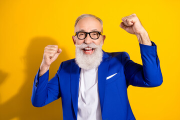 Photo of charming amazed happy old grandfather raise fists winner wear glasses isolated on yellow...