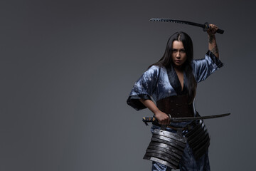 Aggressive woman samurai in fight stance with katanas