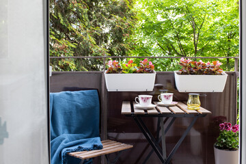 bright small apartment terrace in summer with flowers and coffee table