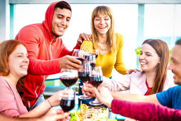 Young people toasting red wine at dinner party on multicolored clothes - Happy drunk friends having fun together at restaurant winery bar - Dinning life style concept