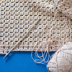 Crochet with beige cotton threads on a blue background.