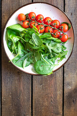 fresh vegetable salad tomato cherry veggie green leaves mix greens spinach, arugula, lettuce ingredient on the table healthy food meal copy space food background 